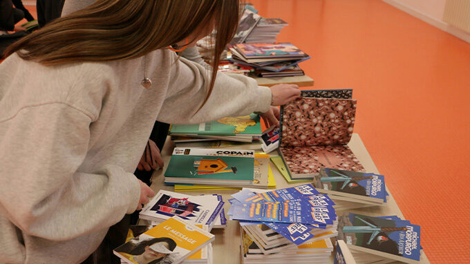 des piles de livres sur une table avec ado qui en regarde un